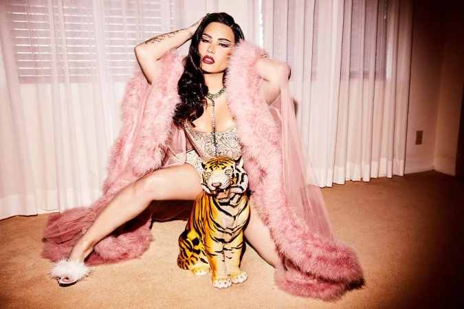 Adult female in lingerie and pink robe poses with a decorative tiger in an indoor setting with window blinds and peach carpet.