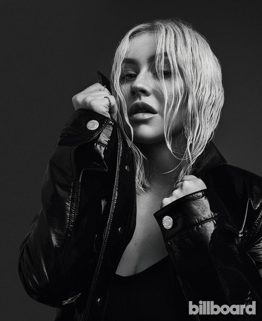 Black-and-white headshot of Christina Aguilera wearing a black jacket. She is looking at the camera with a slight smile.