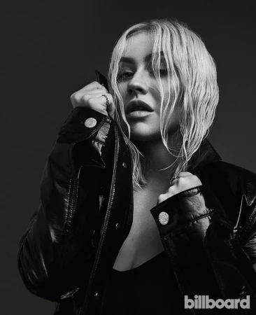 Black-and-white headshot of Christina Aguilera wearing a black jacket. She is looking at the camera with a slight smile.