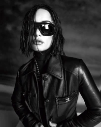 Portrait of a woman with wet hair wearing oversized sunglasses and a leather jacket in a black and white editorial style.