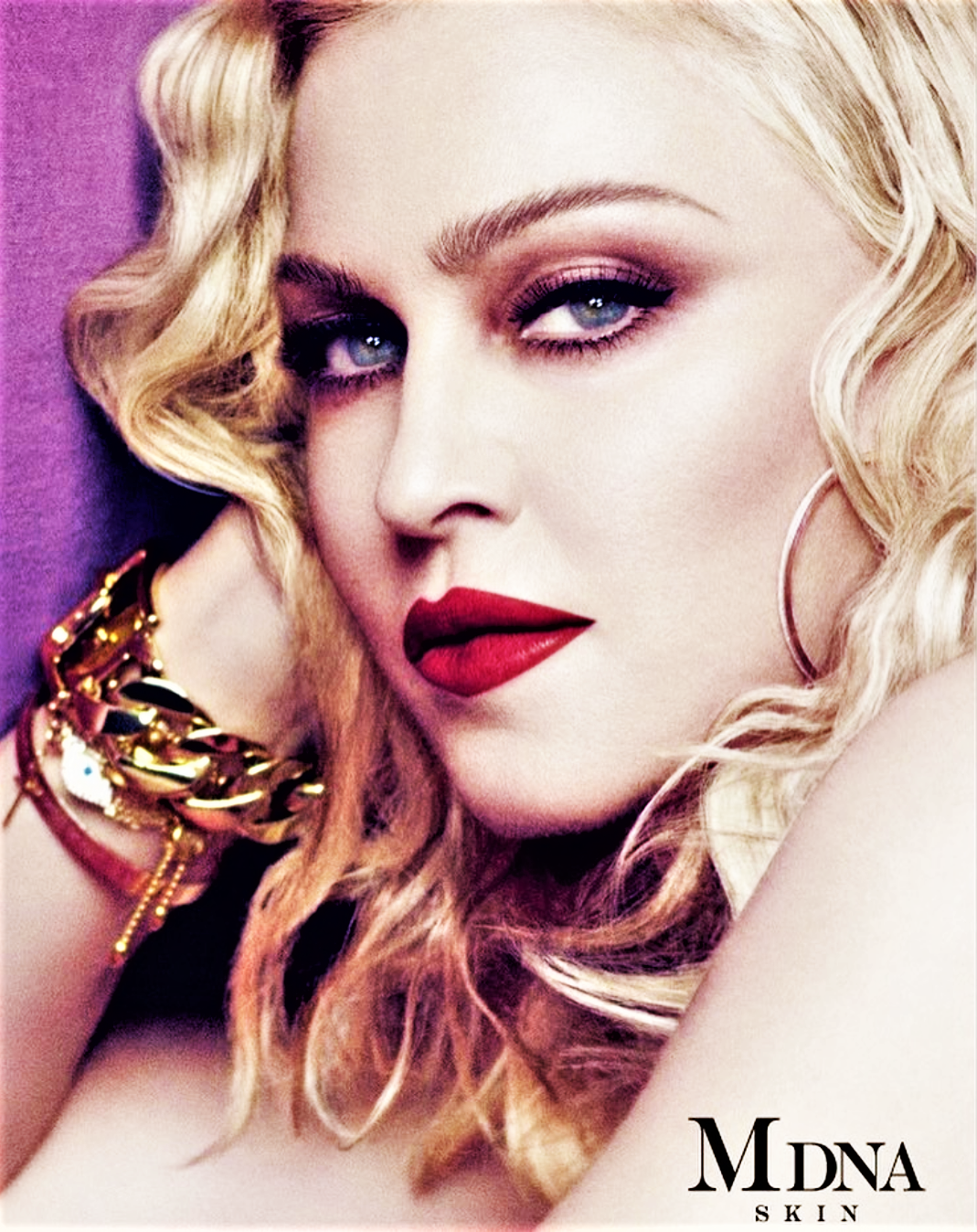 Close-up of an adult female model with blonde wavy hair and bright red lipstick posing in a beauty or fashion context.