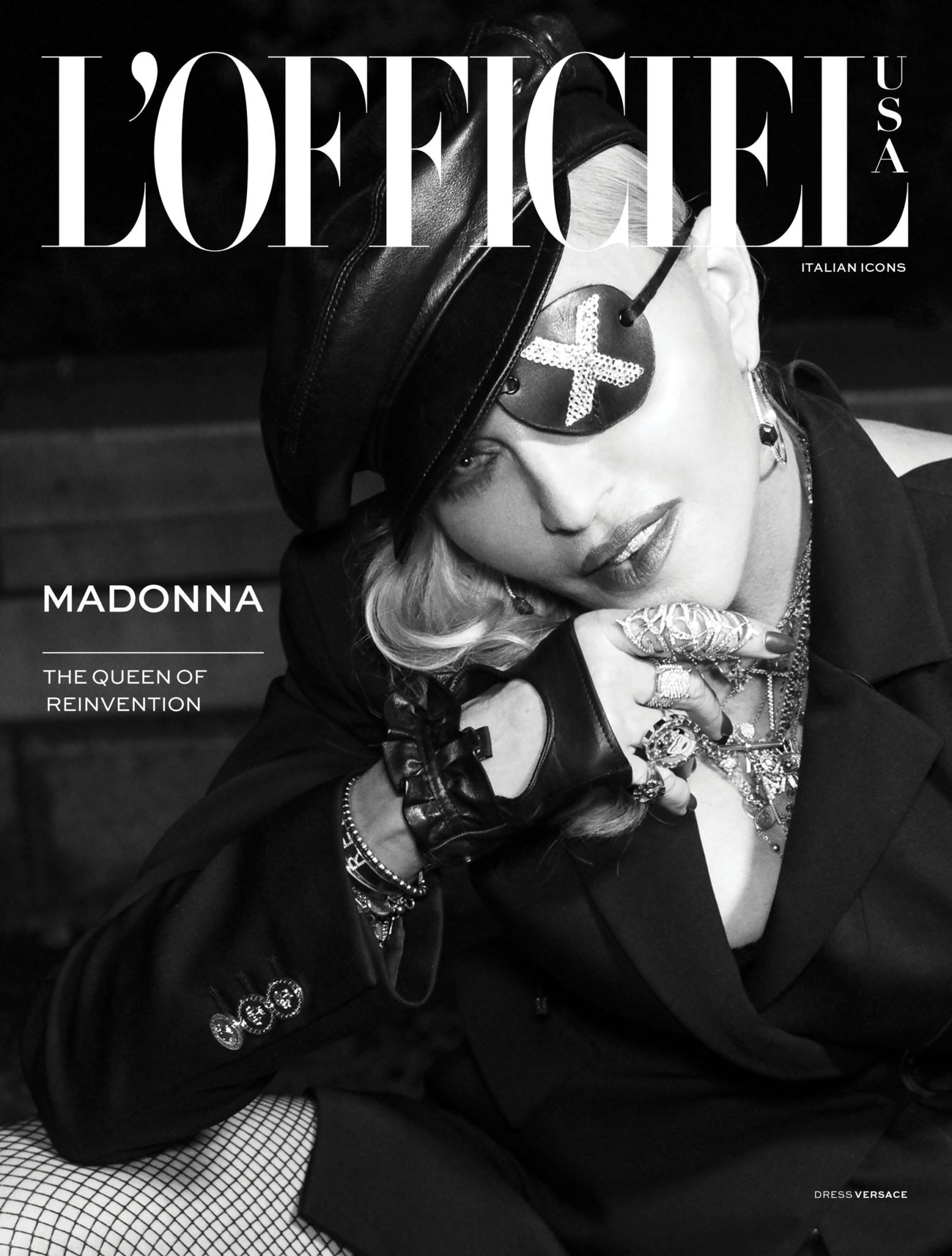 Black-and-white magazine cover featuring a celebrity wearing an eyepatch, hat, blazer, gloves, and heavy jewellery, shot indoors.