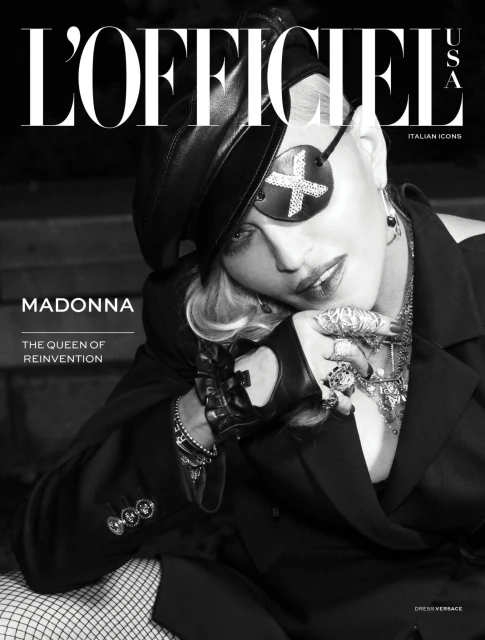 Black-and-white magazine cover featuring a celebrity wearing an eyepatch, hat, blazer, gloves, and heavy jewellery, shot indoors.
