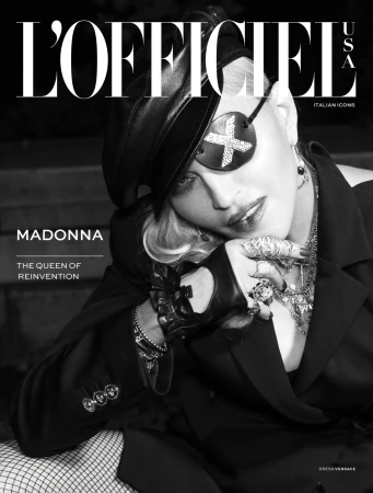 Black-and-white magazine cover featuring a celebrity wearing an eyepatch, hat, blazer, gloves, and heavy jewellery, shot indoors.