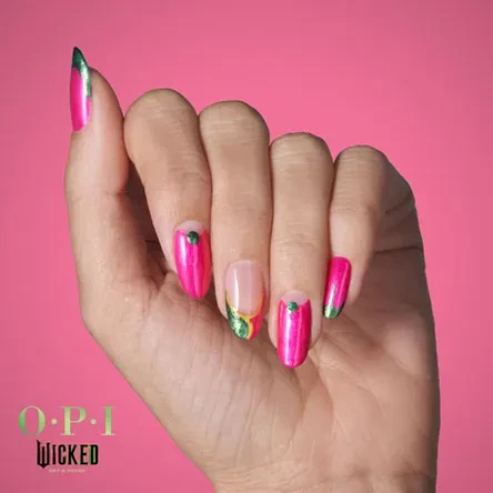 Close-up of a hand displaying pink and green nail art against a pink background, featuring the OPI Wicked logo.