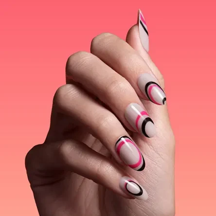 Close-up of a woman's hand featuring oval-shaped stiletto nails with a nude base and black and pink circular nail art design.