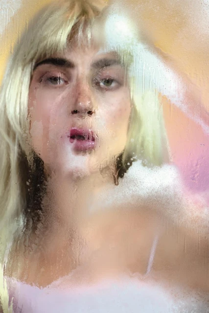 Close-up portrait of a young adult female with blonde hair and pink lipstick, seen through a steamy glass with water droplets.