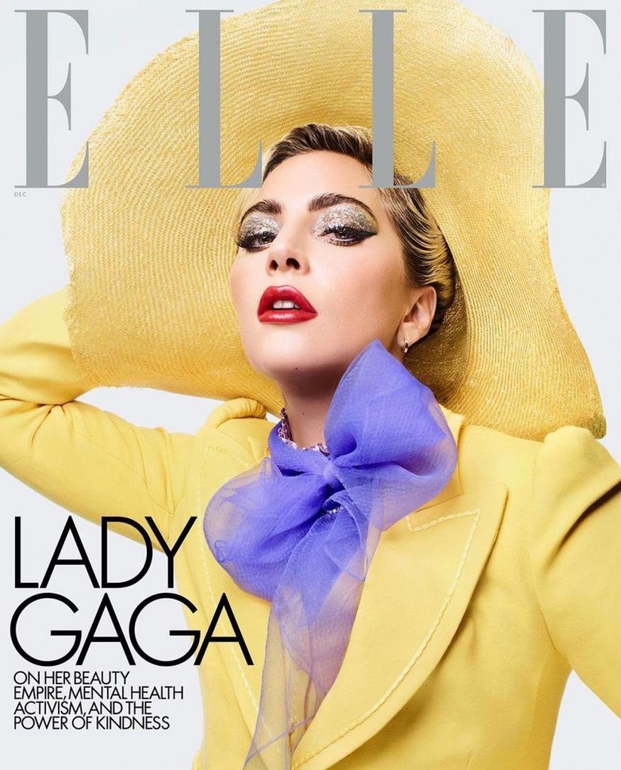 Elle magazine cover featuring Lady Gaga wearing a yellow hat and blazer with a purple scarf, posing in a photo studio.