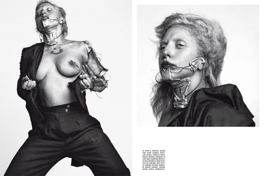 Avant-garde fashion shot featuring a woman with chest bared, metal prosthetic additions, styled dark suit, set against a light backdrop.