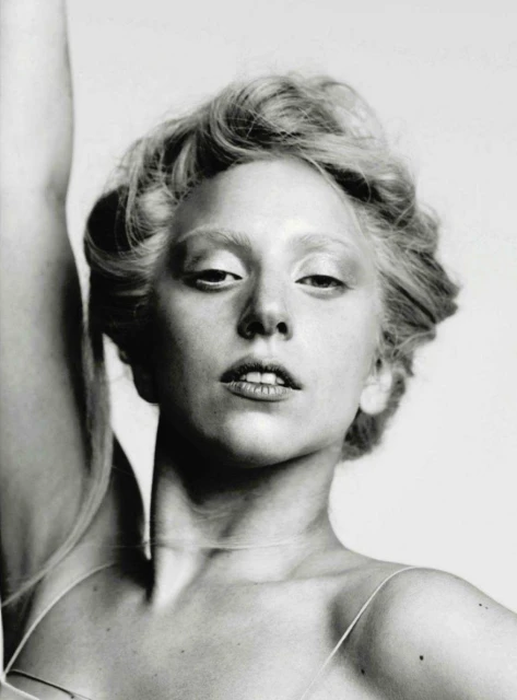 Black and white portrait of a woman with fair skin, light eyebrows, and light hair, gazing directly at the camera with a subtle expression.
