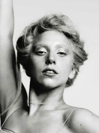 Black and white portrait of a woman with fair skin, light eyebrows, and light hair, gazing directly at the camera with a subtle expression.