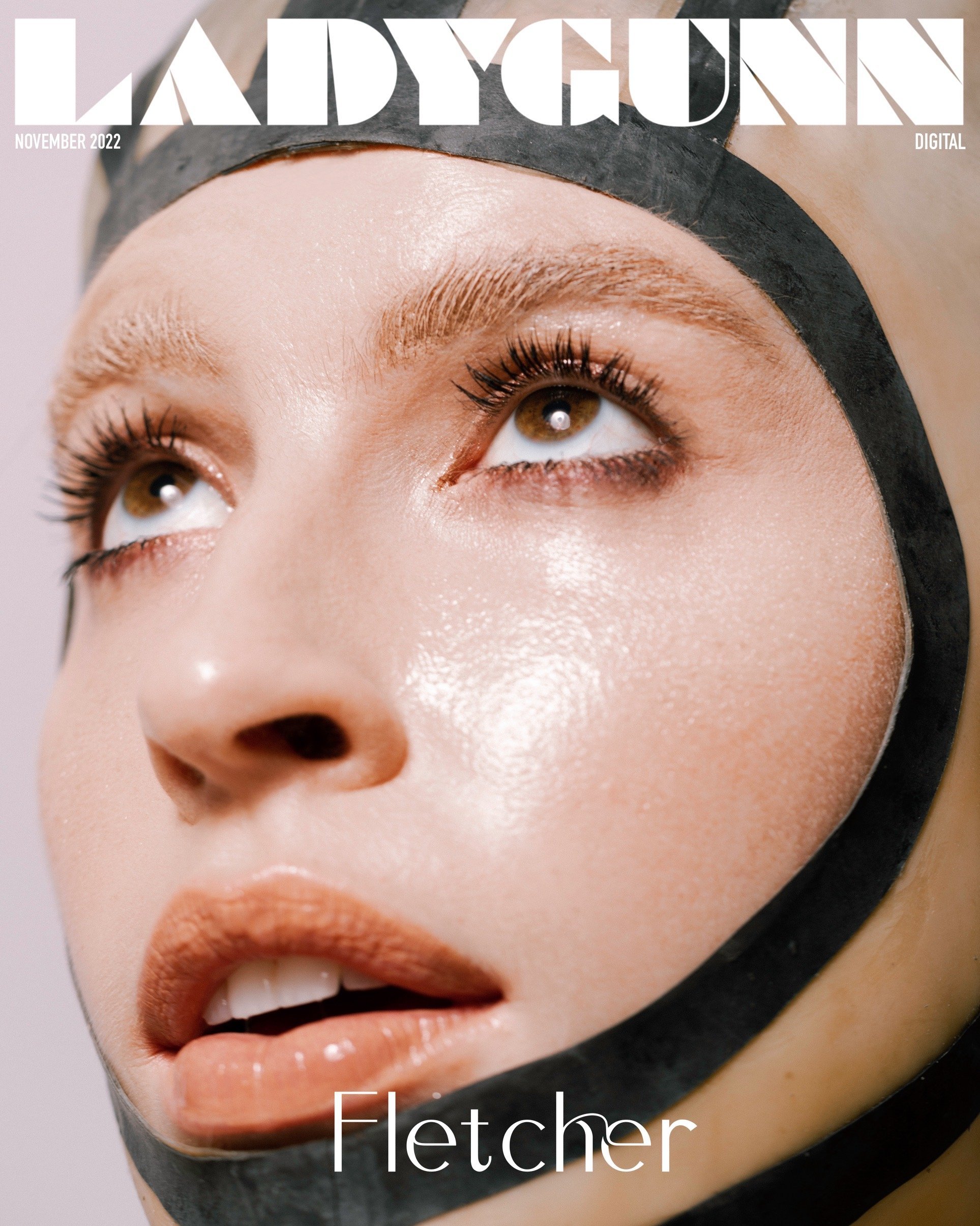 Ladygunn Magazine cover featuring a close-up of Fletcher, eyes looking up, wearing a black latex hood. Magazine text visible.