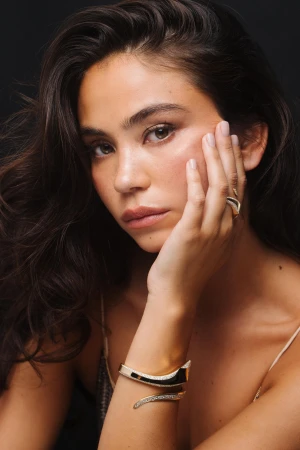 Close-up portrait of a woman with dark hair wearing gold jewelry photographed by Gabriel Perez Silva
