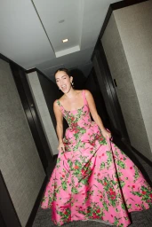 Woman in pink floral ball gown laughing while walking down a hotel hallway captured by photographer Gabriel Perez Silva.