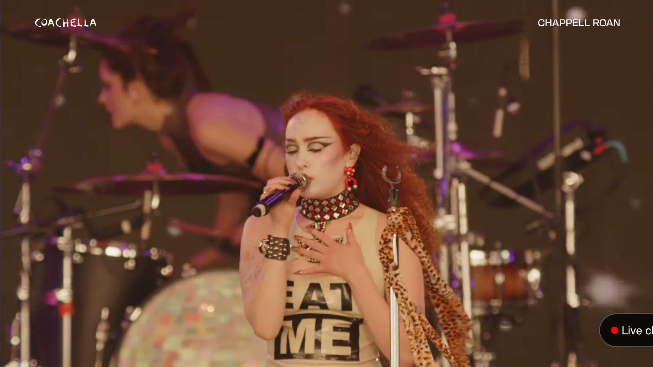 Chappell Roan performs at Coachella with red hair, black and white shirt, and a backup drummer on stage with a drum kit.