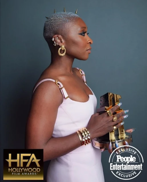 Profile shot of a woman with short grey hair and gold spike accents holding an award at a Hollywood Film Awards event.