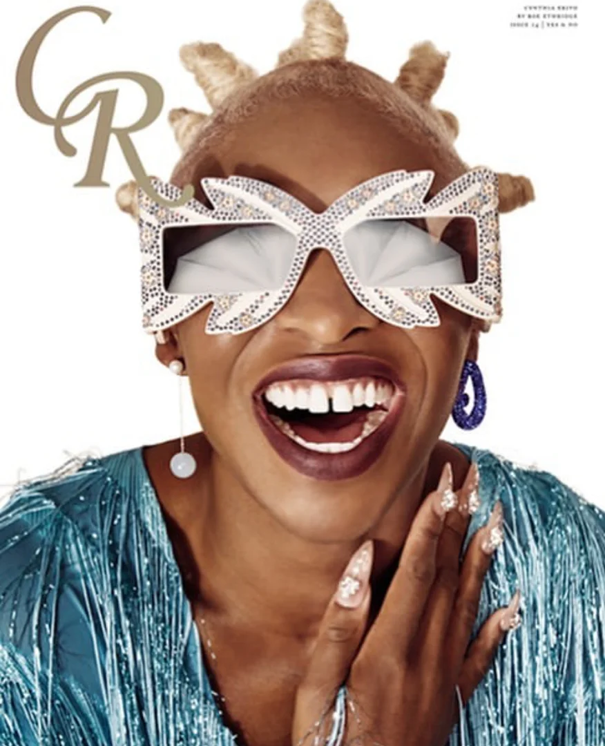 Magazine cover featuring a smiling Black woman with blonde hair, bedazzled glasses, and a blue sequin dress against a white background.