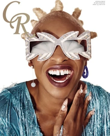 Magazine cover featuring a smiling Black woman with blonde hair, bedazzled glasses, and a blue sequin dress against a white background.