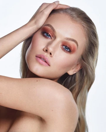 Close-up portrait of a blonde woman with warm copper eyeshadow and soft pink lips by make-up artist Jacinta Spencer.