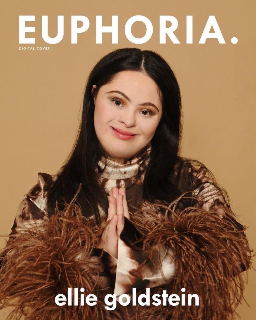 Euphoria magazine cover featuring Ellie Goldstein, a woman with Down syndrome, posing in a brown feathery top against a tan backdrop.