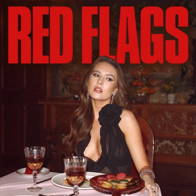 Woman in a black dress sits at a table with wine glasses and macarons, illuminated by warm, soft light. 'RED FLAGS' in red text.