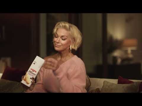 Elegant woman in a cozy setting holds a box of Milano cookies, creating a warm, inviting moment of indulgence and relaxation.