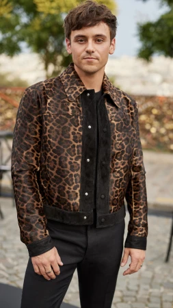 Man wearing a leopard print jacket with black trousers standing outdoors on a paved street styled by James Yardley