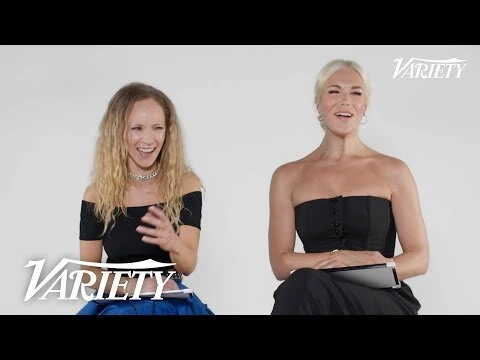 Two smiling women sit side-by-side in a bright studio, dressed in black tops, as they participate in a video interview for Variety.