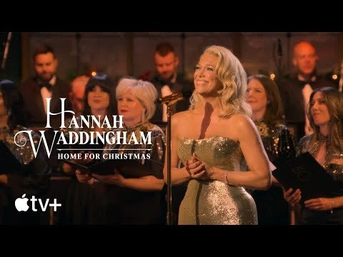 Hannah Waddingham sings center stage in a sparkly strapless dress, backed by a choir, warm lighting, and the Apple TV+ logo.
