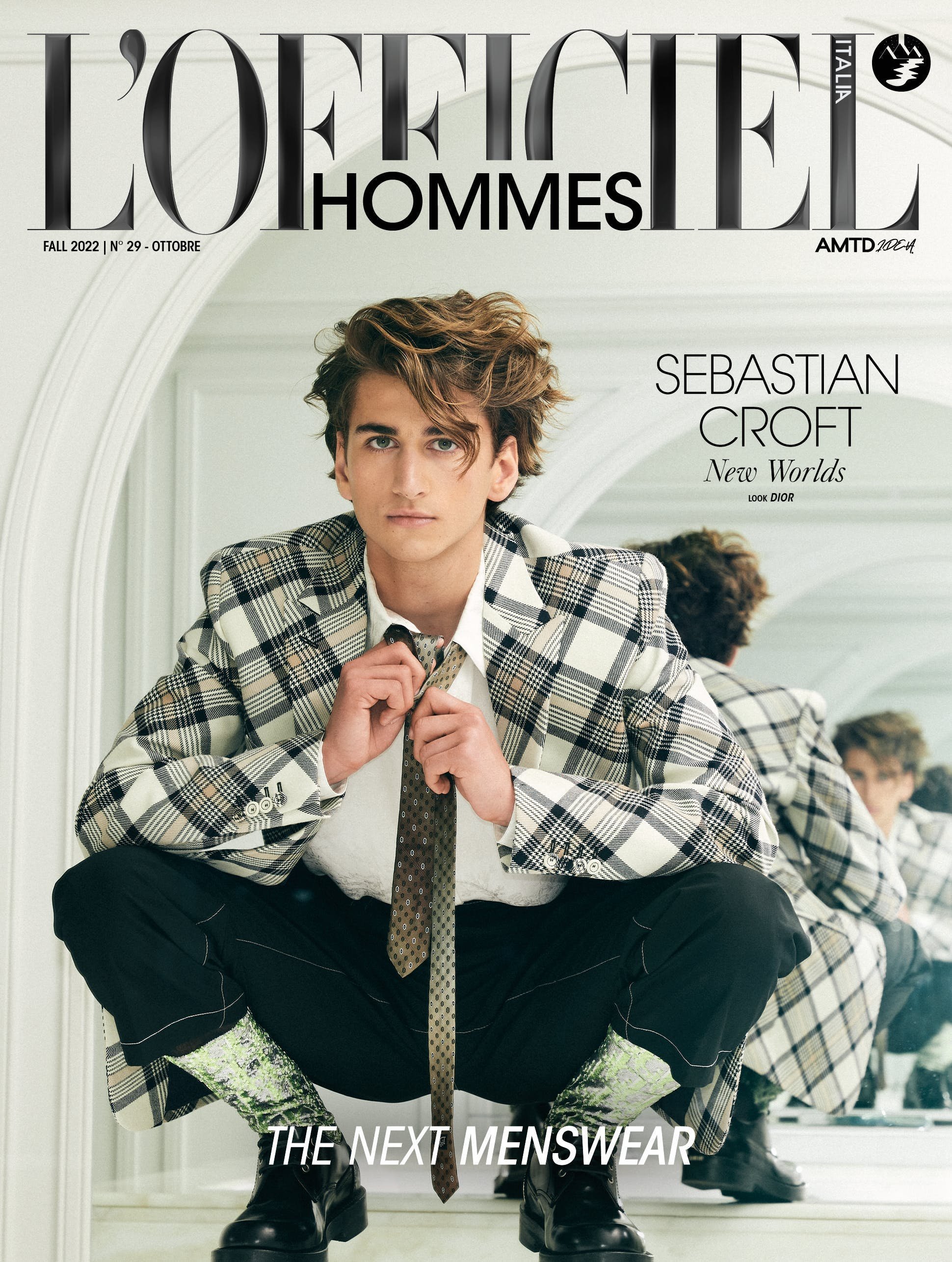 Magazine cover featuring a young adult male with tousled brown hair, posing in a plaid blazer and untied tie, crouching indoors.