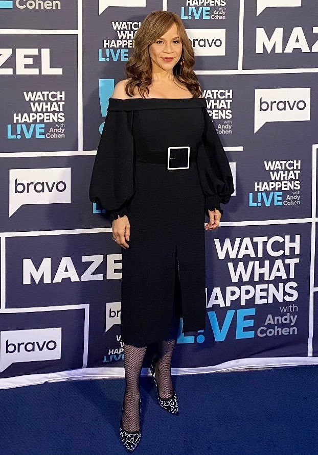 Rosie Perez poses in a black off-the-shoulder midi dress with a square belt buckle at 'Watch What Happens Live' with Andy Cohen.