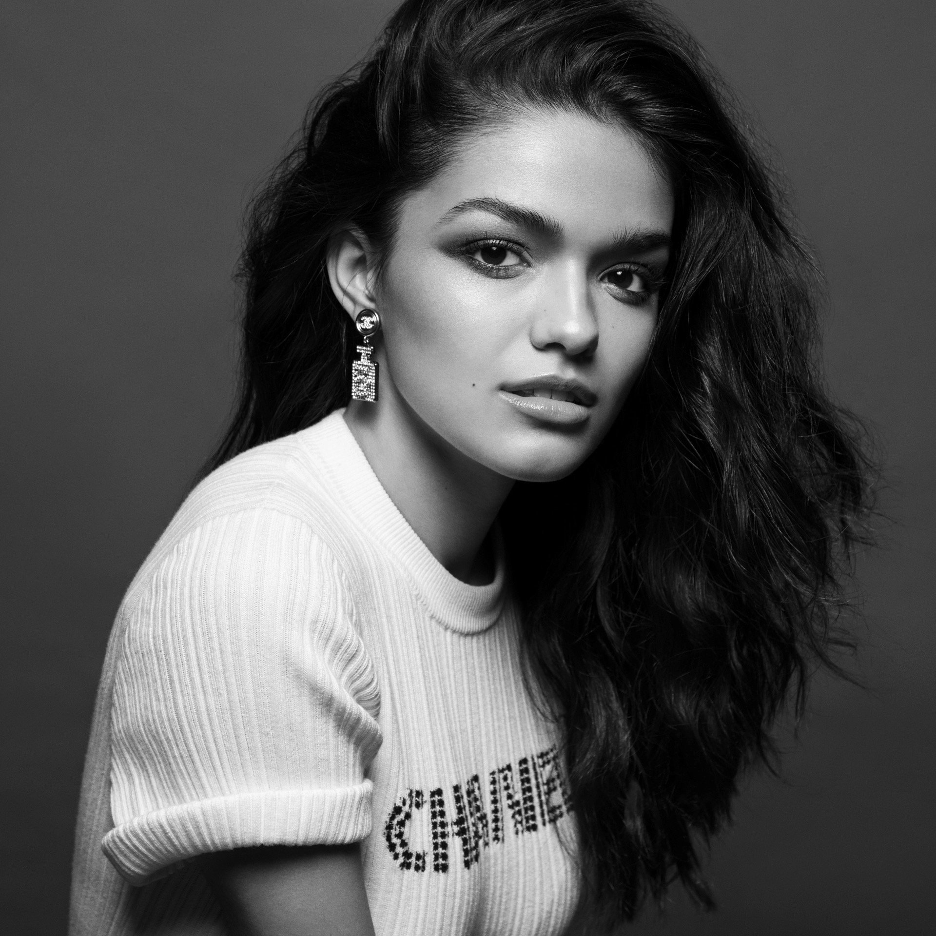 Monochrome portrait of a woman with dark wavy hair wearing a white top and drop earrings styled by Jared Depriest