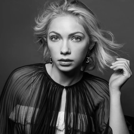 Black and white portrait of a blonde woman wearing a pleated sheer cape and statement earrings styled by Jared Depriest