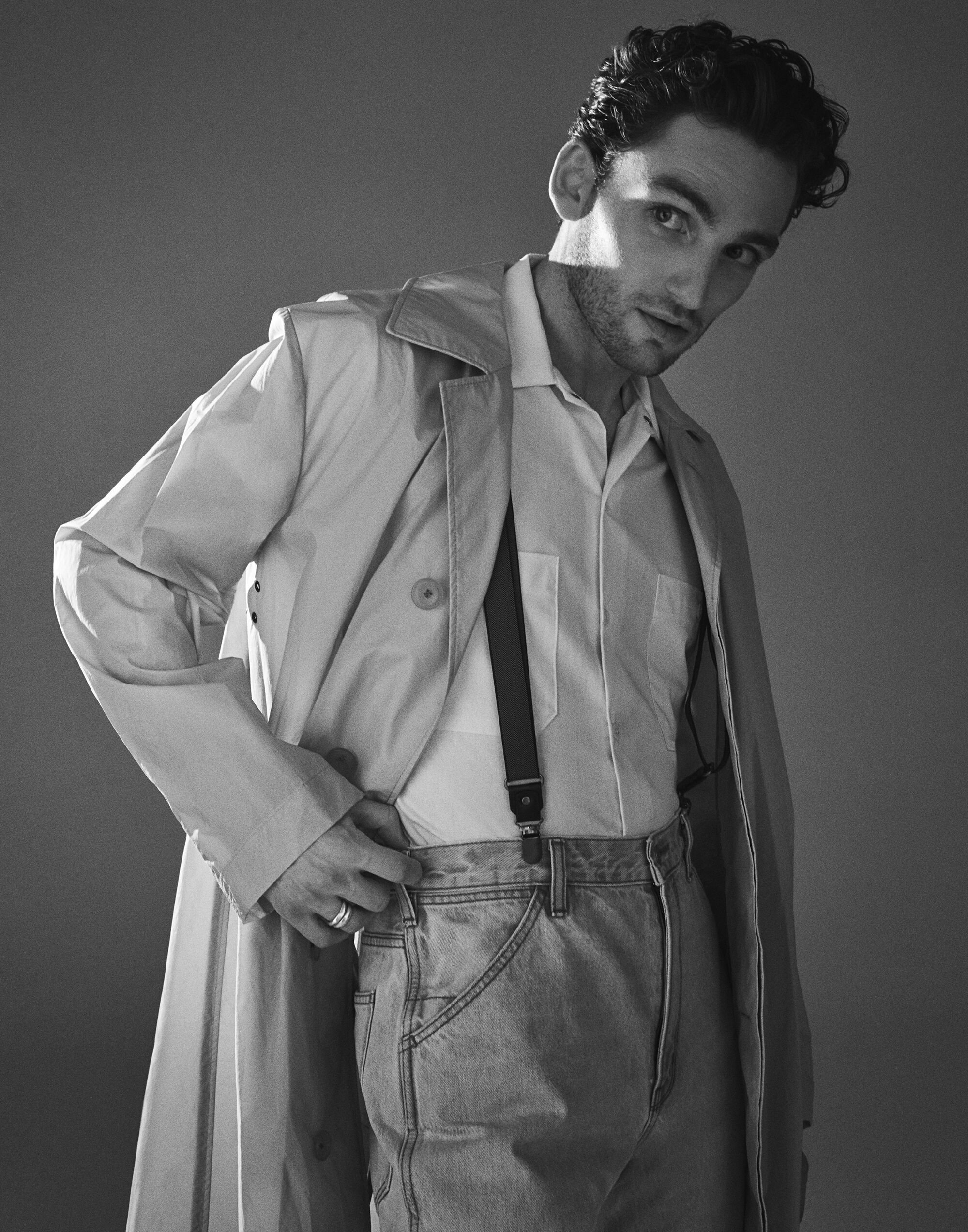 Black and white portrait of a man wearing a trench coat, button-down shirt, and suspenders in New York.