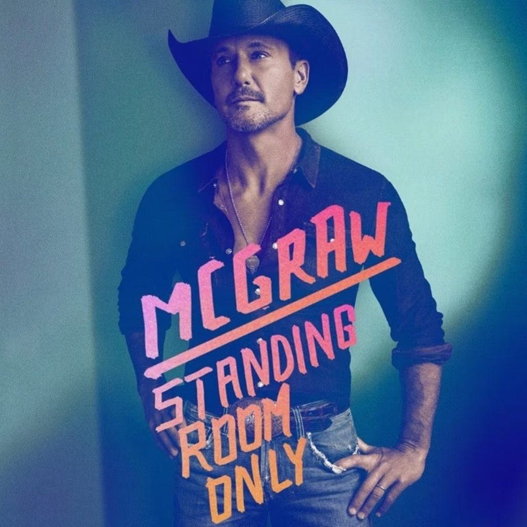 Portrait of Tim McGraw wearing a black cowboy hat and a black denim shirt, posing against a teal-colored wall with text overlay.