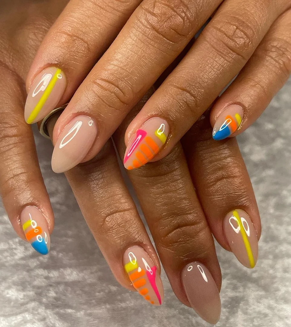 Close-up of hands showcasing almond-shaped nails with nude polish and colorful geometric nail art with lines and abstract shapes.