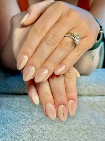 Close-up of a woman's hands showcasing a geometric-design manicure with nude and light-pink nail polish and wearing an engagement ring.