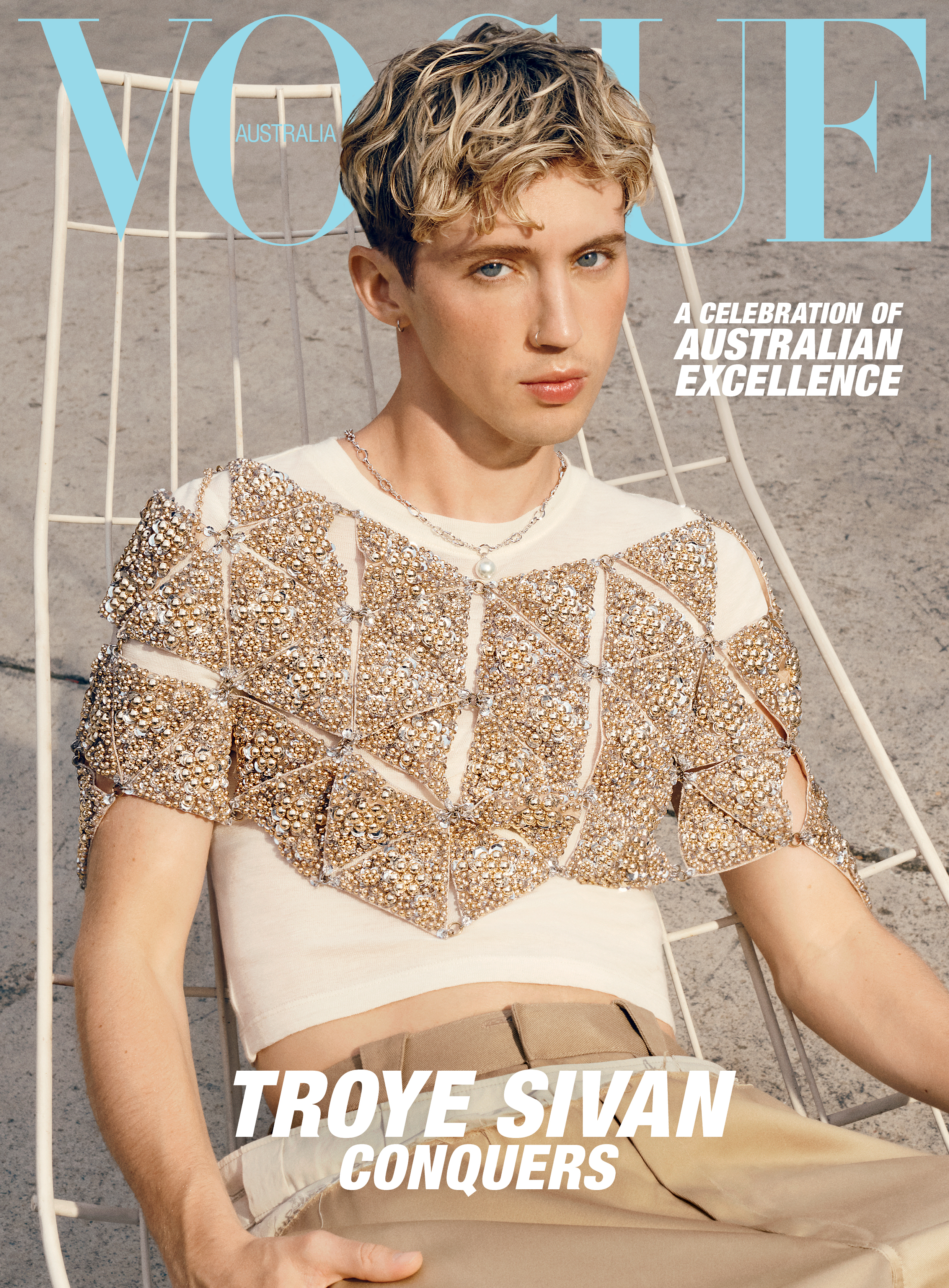 Vogue Australia cover featuring Troye Sivan wearing a beaded white top, posing in a white chair against a neutral backdrop.