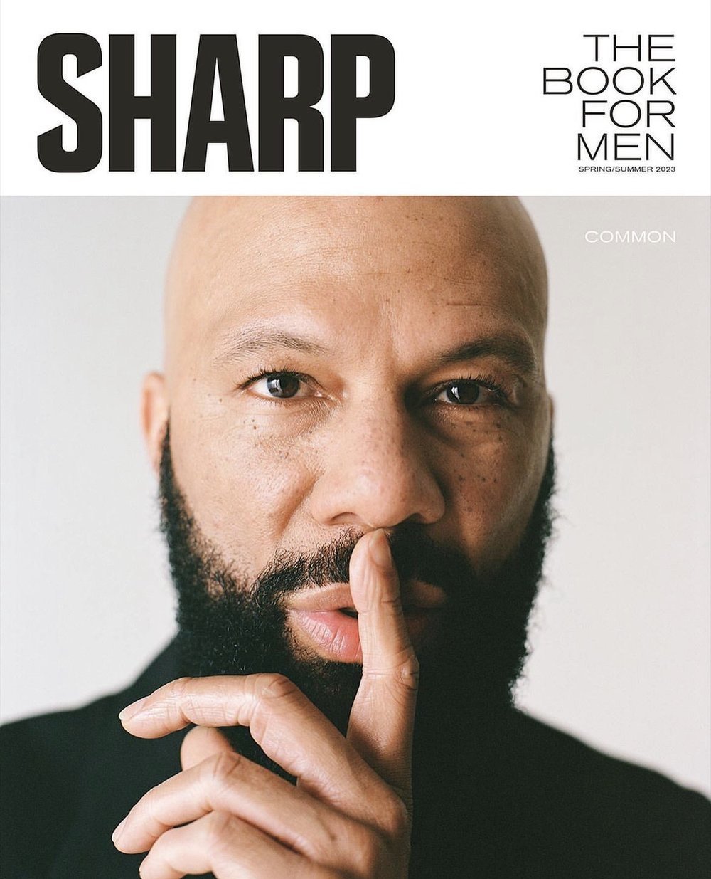 Close-up portrait of American rapper and actor Common with finger held to lips, styled by Jay Hines