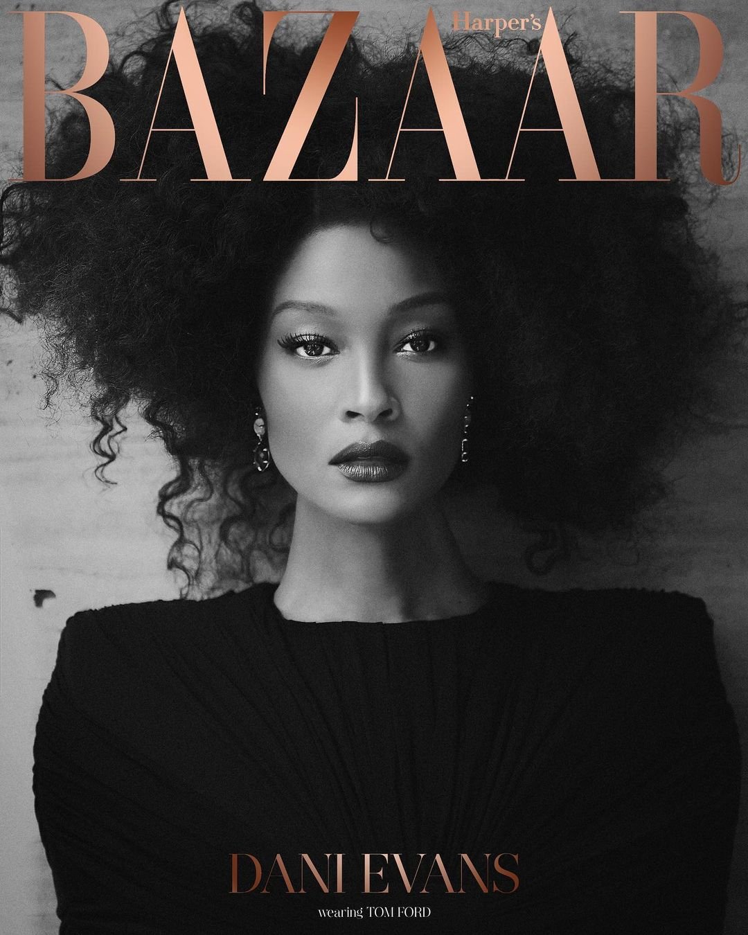 Close-up fashion portrait on magazine cover. Dani Evans poses with afro, wearing a black dress, against neutral background, with Bazaar masthead.