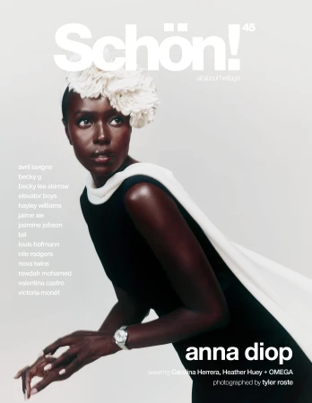 Magazine cover featuring a Black woman wearing a black dress and a white flower headpiece against a pale backdrop in a studio shot.
