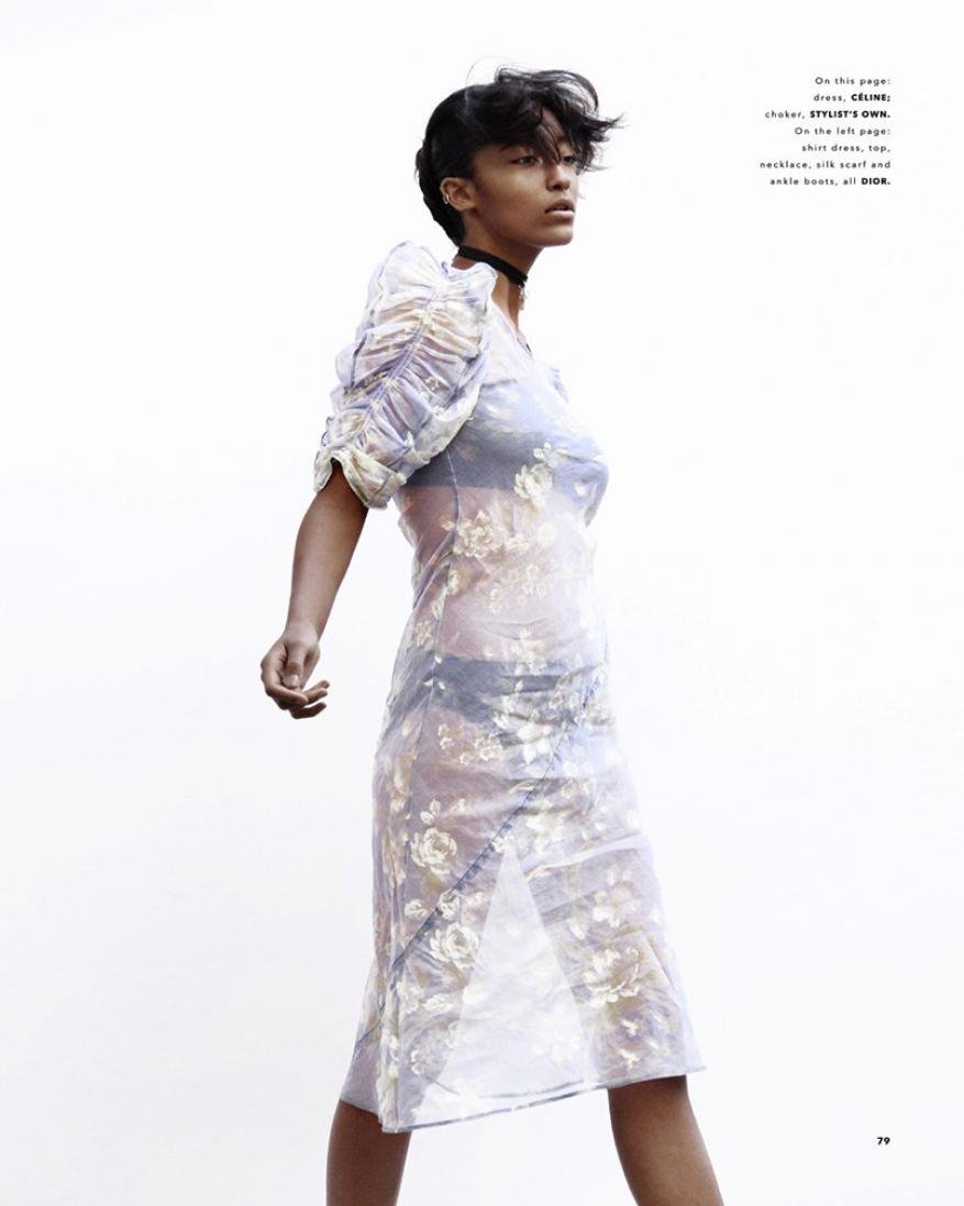 Fashion editorial shot of a Black female model wearing a floral print dress, posing against a bright white background in a studio setting.