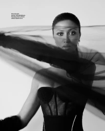 Black and white portrait of a woman wearing a strapless black corset with sheer veil draped horizontally across her face
