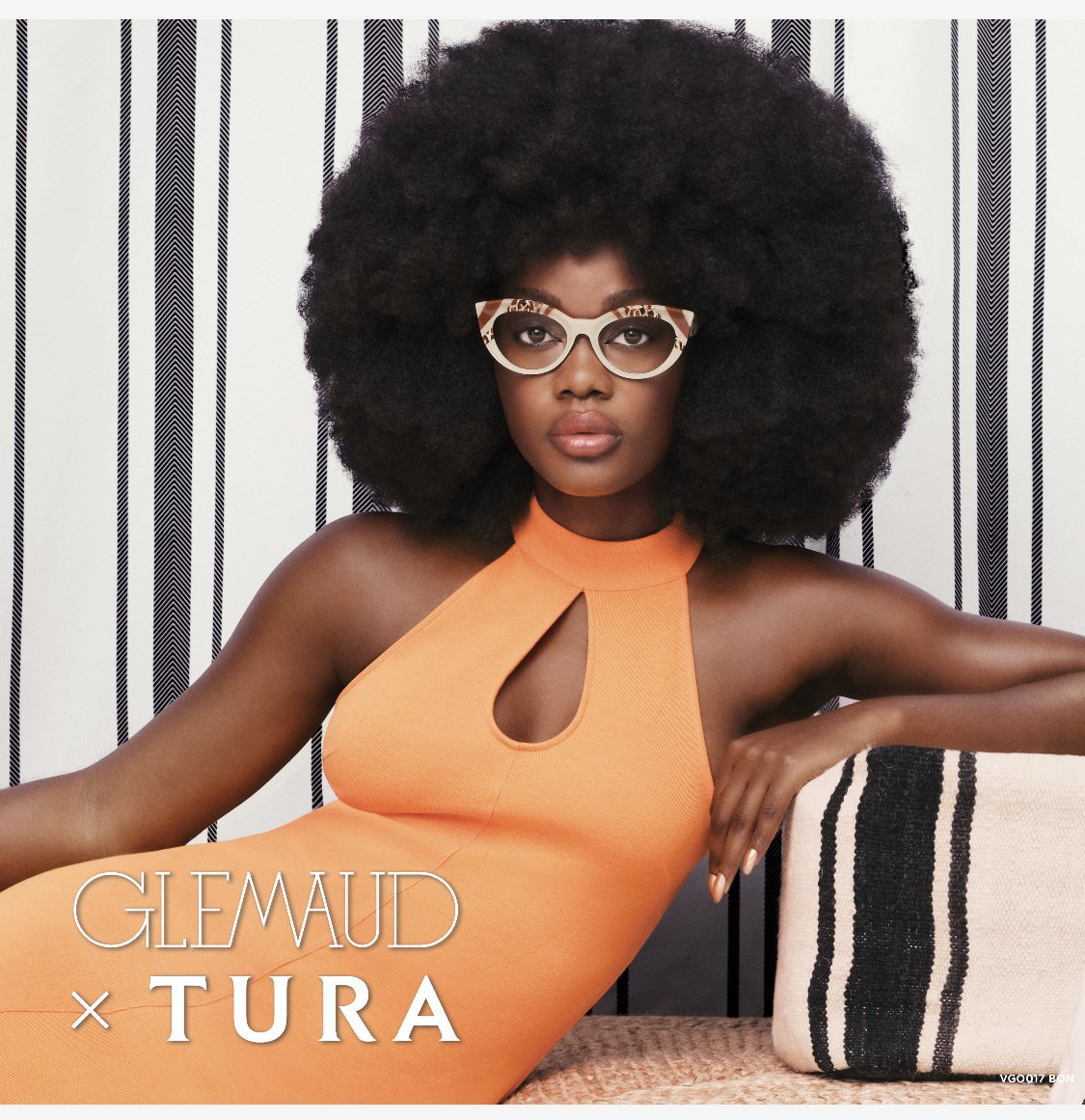A dark-skinned female model poses in an orange dress and glasses against a striped backdrop. The image promotes the eyewear brand Tura.