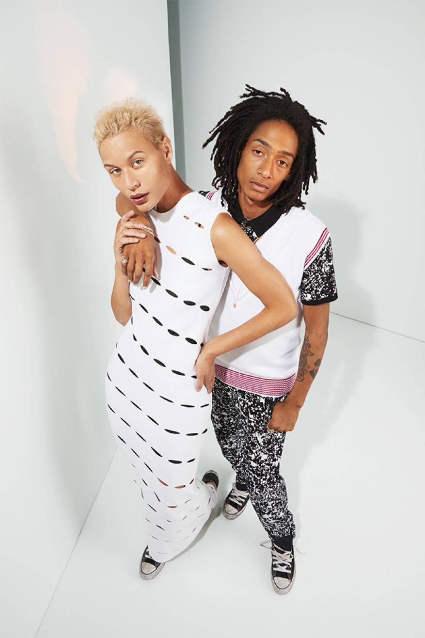 A couple in fashionable outfits poses in a photo studio with an eye-level angle. The pair is wearing black and white patterned clothing.