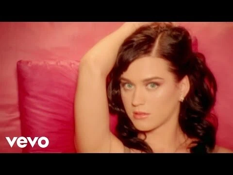 Close-up portrait of a brunette woman with fair skin and light eyes against a backdrop of pink fabrics.