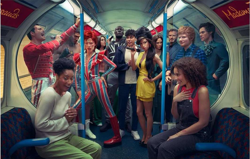 Group of wax figure celebrity impersonators in a London subway train. People are standing and sitting; posed to create a realistic scene.