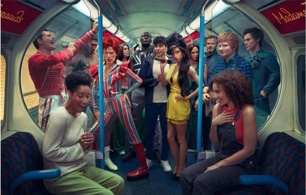 Group of wax figure celebrity impersonators in a London subway train. People are standing and sitting; posed to create a realistic scene.