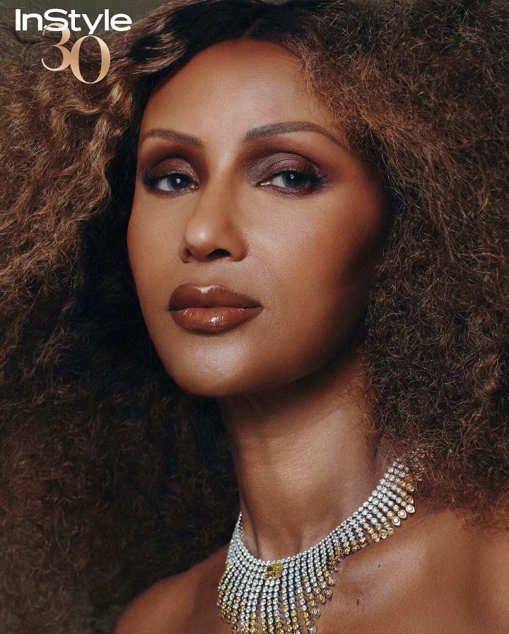 Close-up portrait of an adult woman with brown curly hair wearing a jeweled necklace, as featured in InStyle magazine.