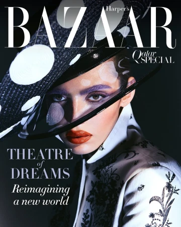 Magazine cover portrait of a woman wearing a large polka dot hat and patterned white jacket with bold purple eye makeup.